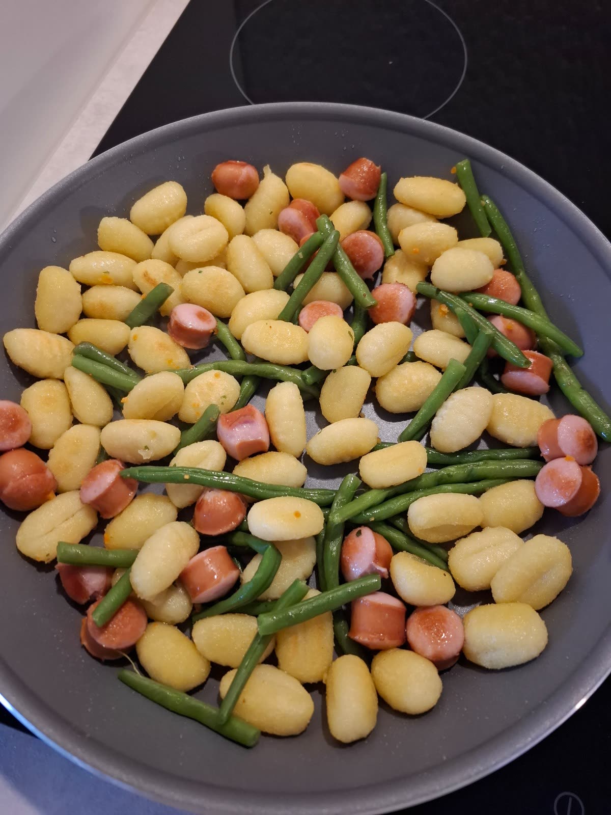 Gnocchi mit grünen Bohnen und kleinen Würstchenstücken in einer Pfanne