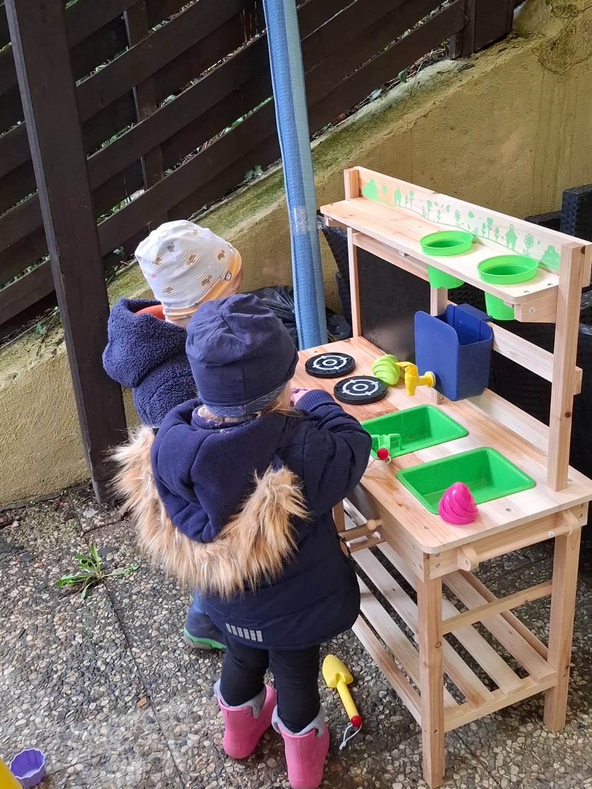 Kinder spielen draußen an der Matschküche