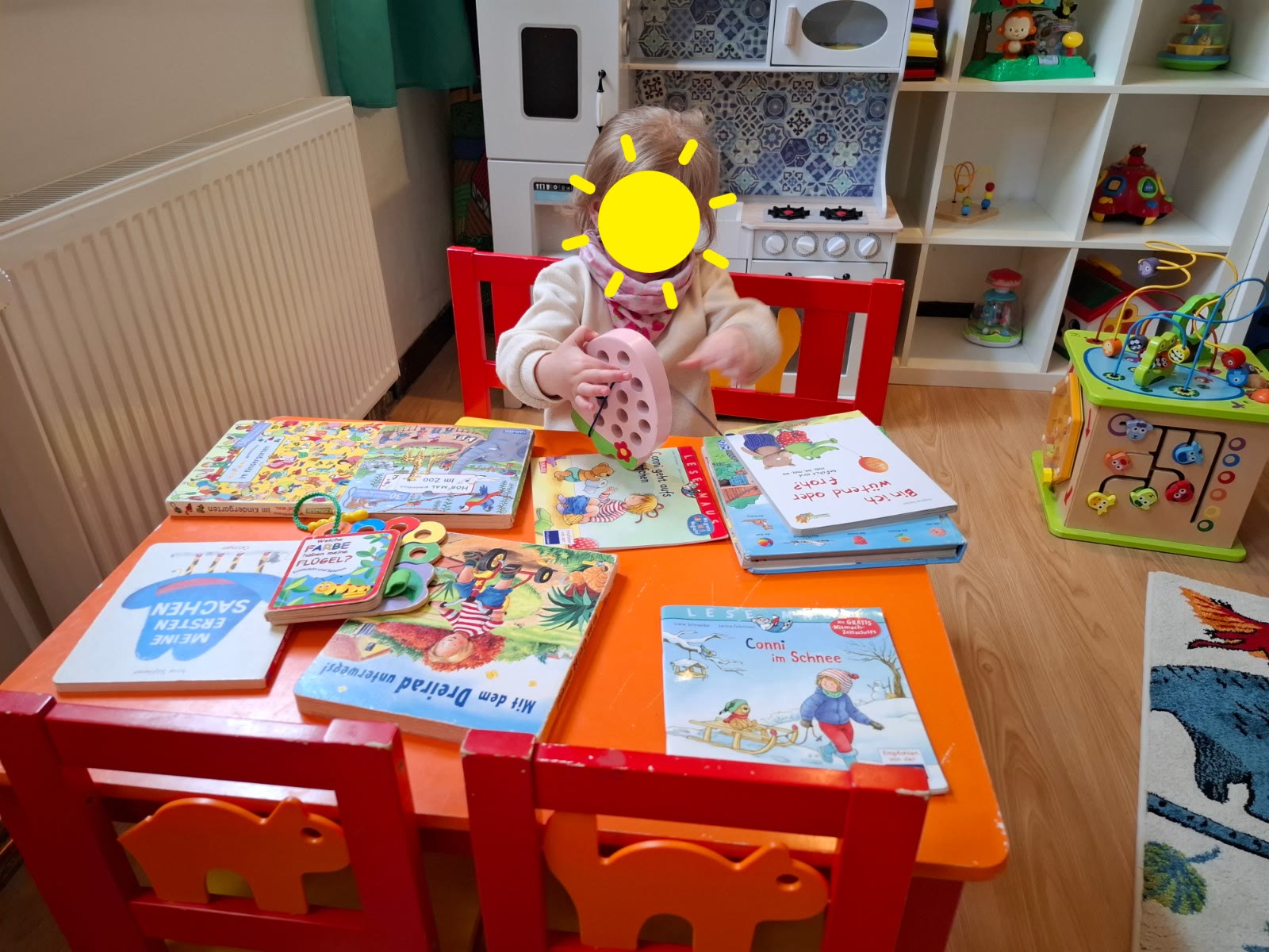 Kind schaut Bilderbücher und Spielmaterial an