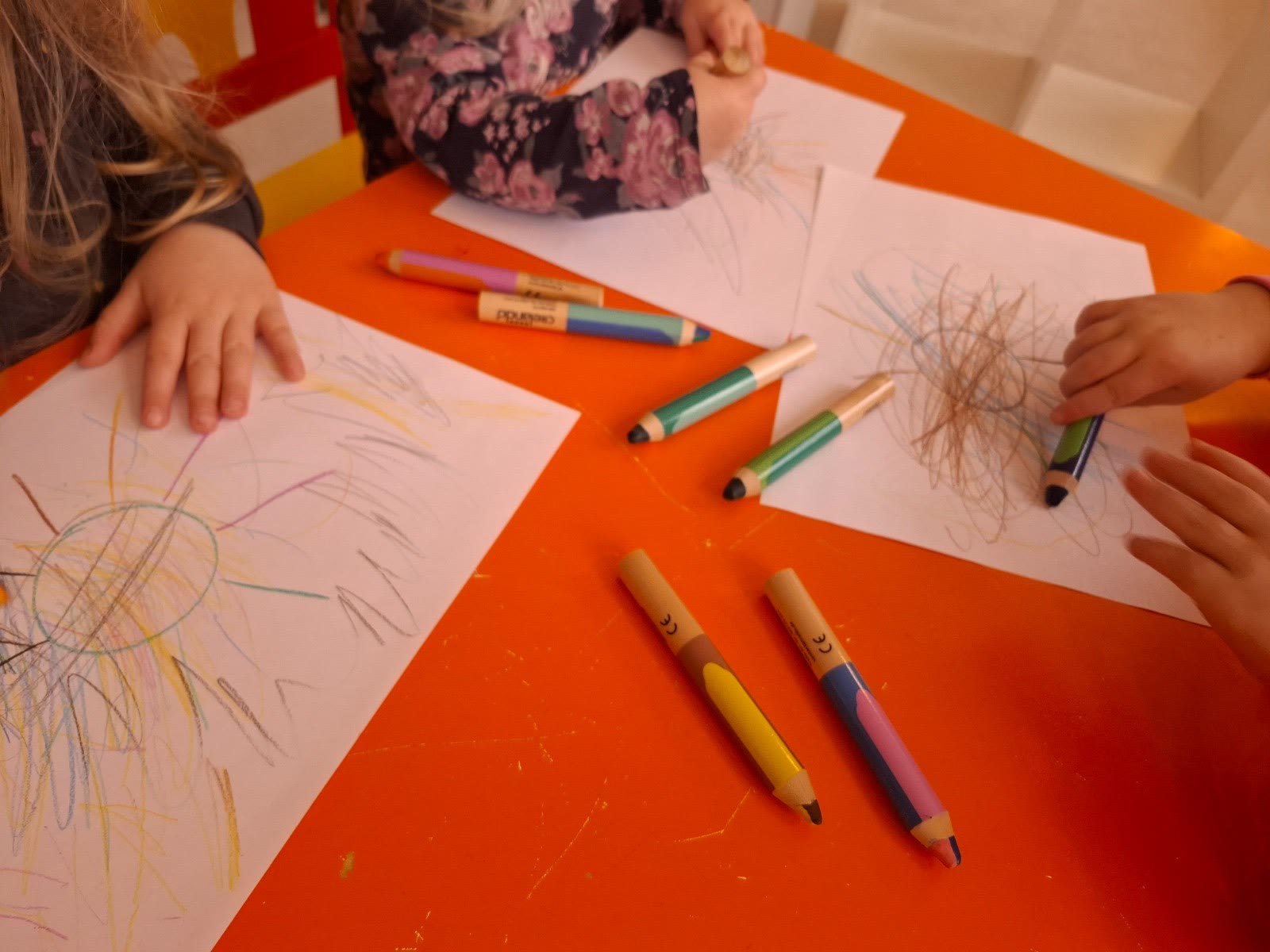 Kinder malen mit bunten Stiften am Tisch