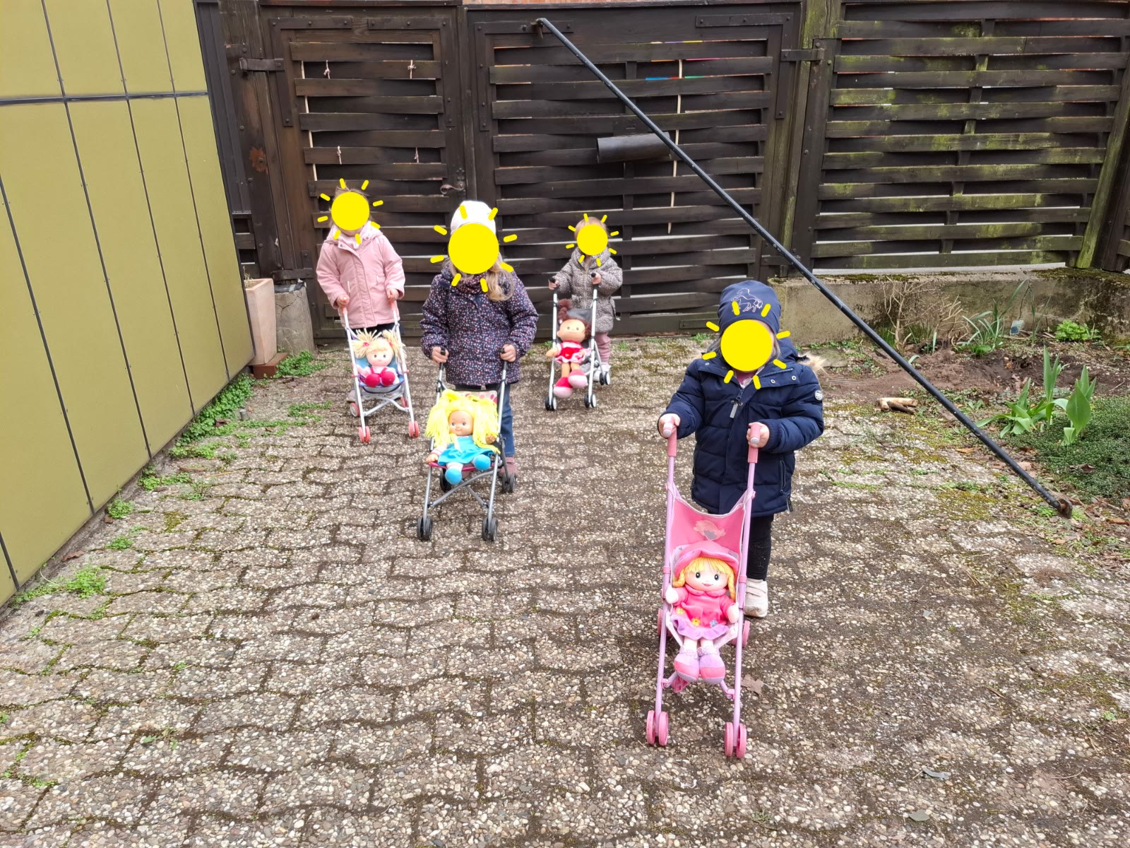 Kinder spielen draußen mit Puppenwagen im Hof