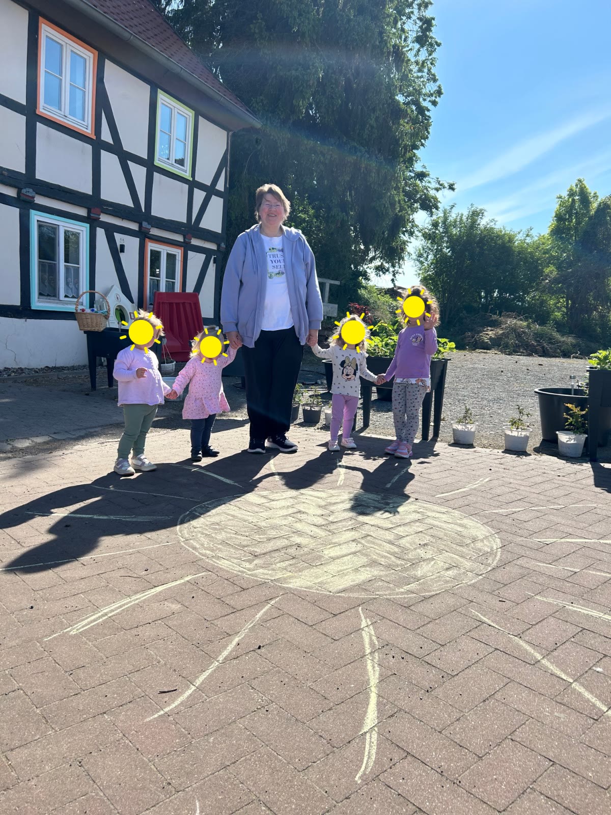 Andrea steht mit Kindern im Hof auf einer gemalten Sonne