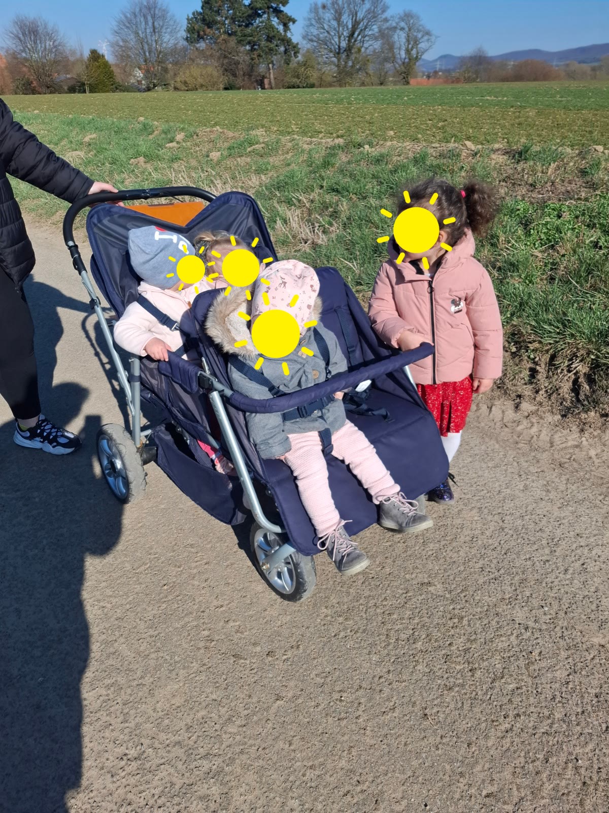 Kinder unterwegs mit Kinderwagen auf einem Feldweg