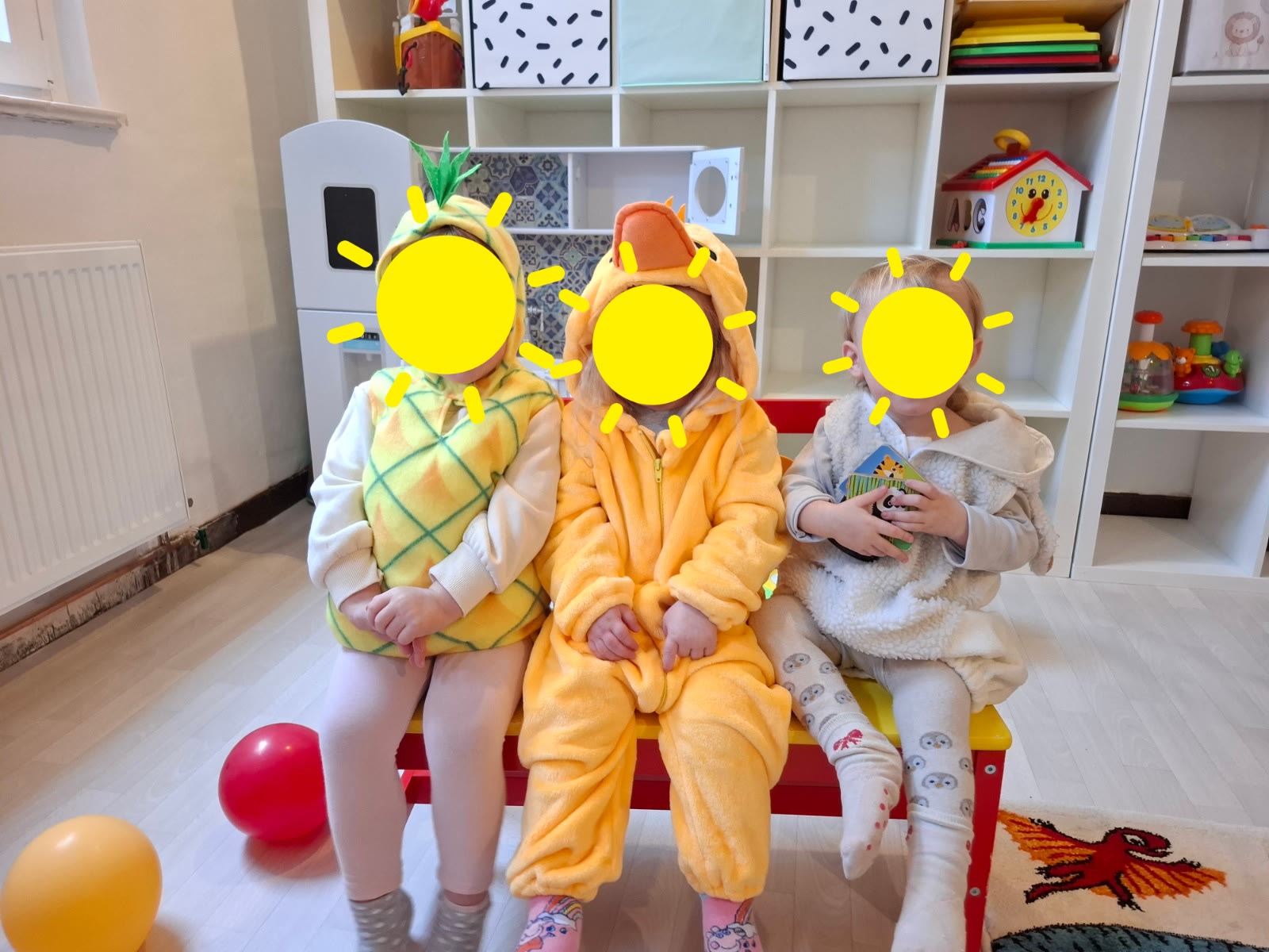 Kinder sitzen verkleidet auf einer Bank im Gruppenraum